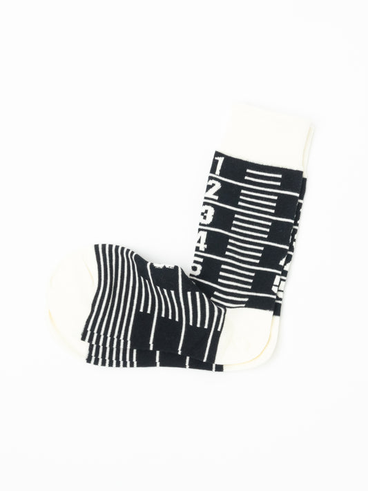 Black and cream Number Sock folded on its side, cream ribbed cuff above a numbered ruler pattern.
