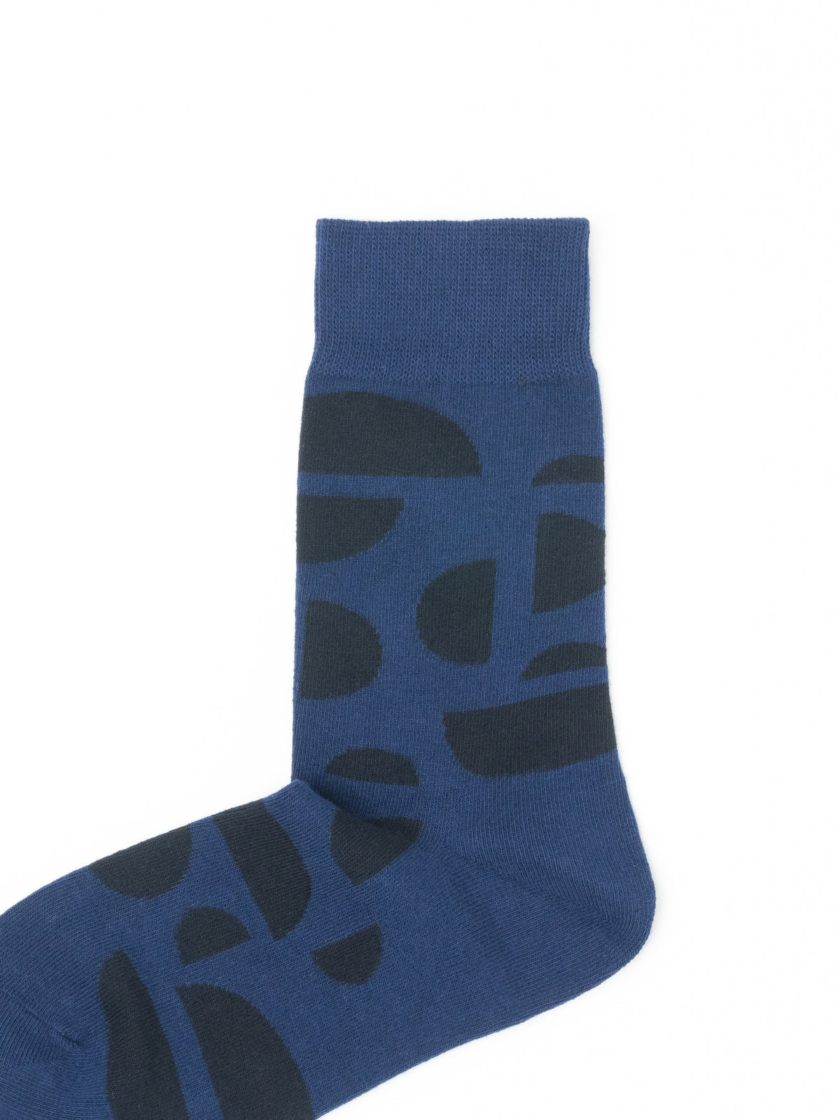 Close-up of a navy blue crew sock showing the dark abstract half-circle pattern and ribbed cuff.