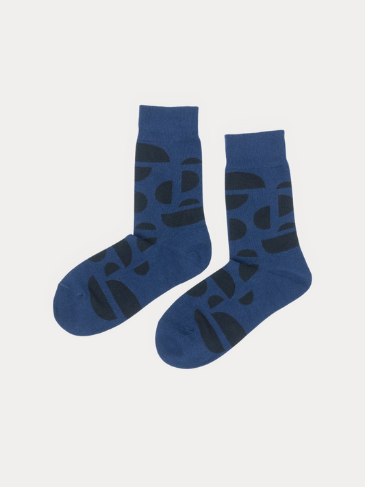 Pair of navy blue crew socks with a dark abstract half-circle pattern, laid flat side by side on a grey background.