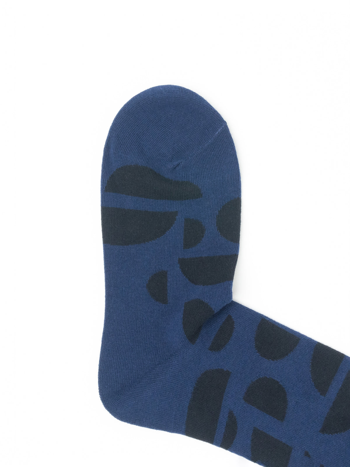 Close-up of the toe of a navy blue crew sock with a dark abstract half-circle print.
