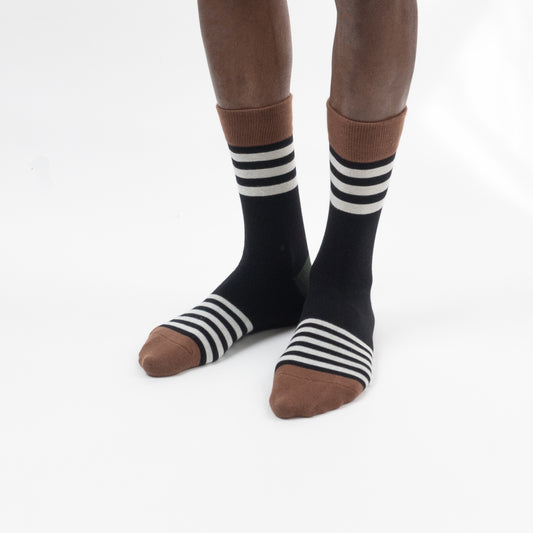Model wearing black crew-length socks with striped details and brown accents against a white background.