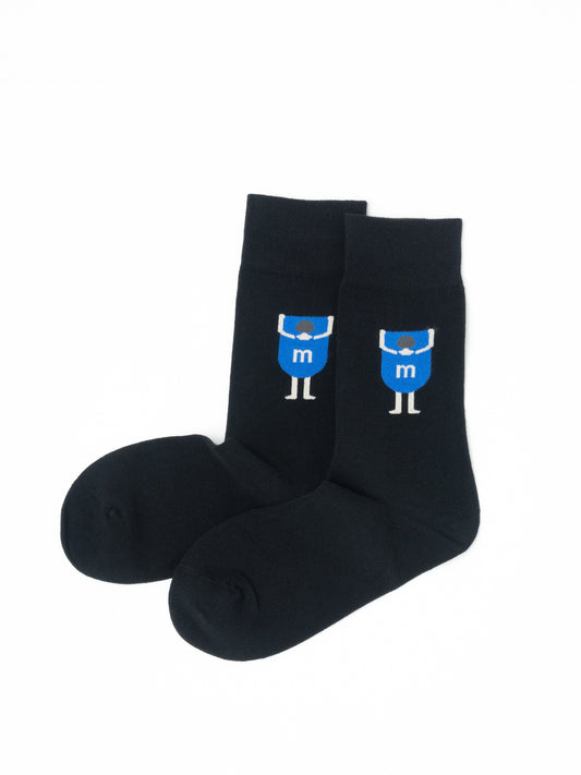 Pair of black crew socks with a blue cartoon figure graphic, laid flat and overlapping at the ankle."