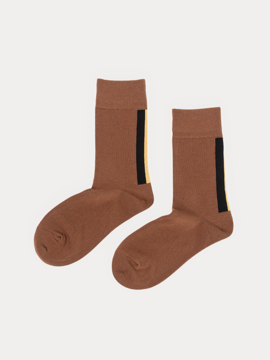 A pair of brown crew socks with a vertical black stripe and a thin yellow accent line near the cuff, displayed on a light gray background.