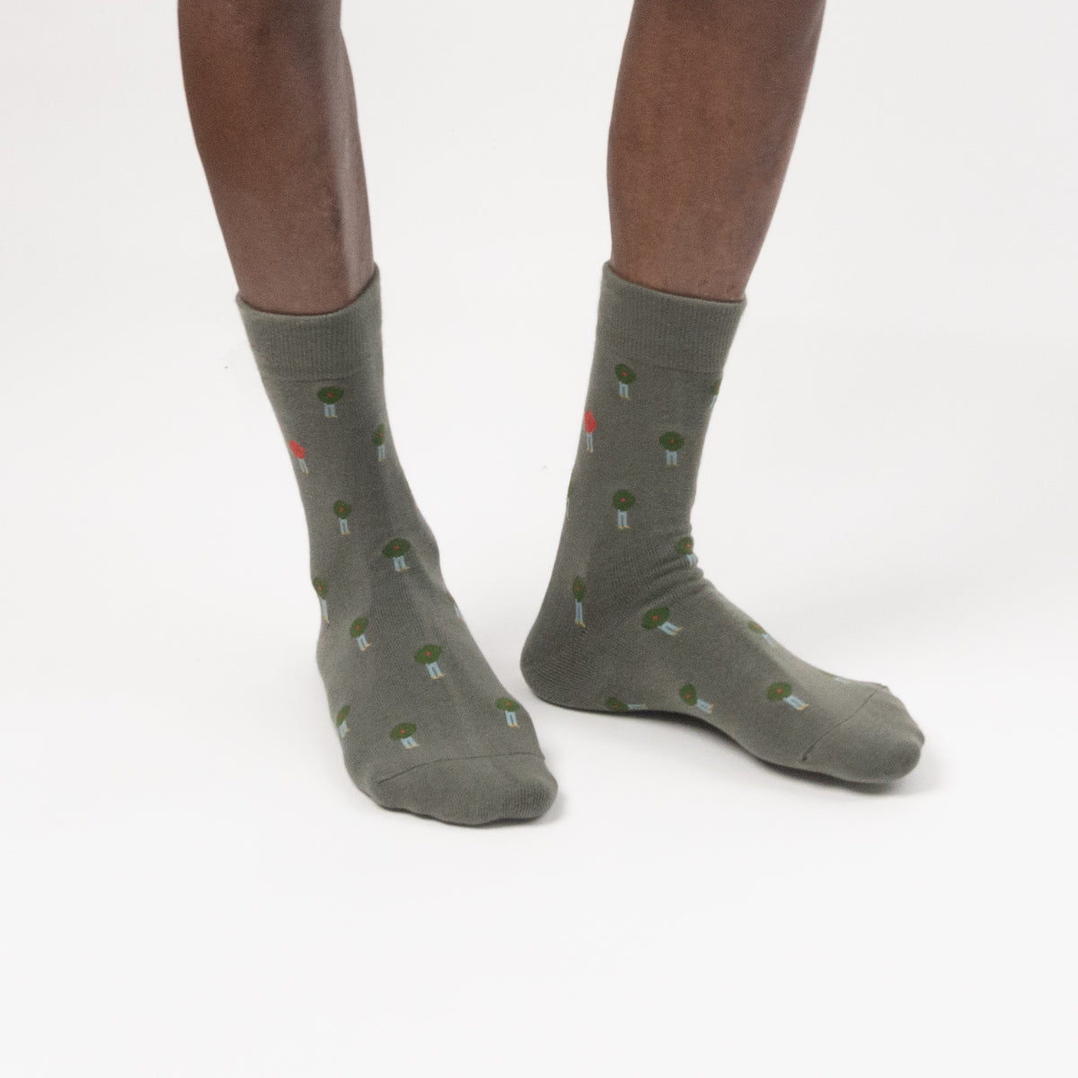 A model in green crew socks with a small green and red button pattern, photographed against a clean white studio background.