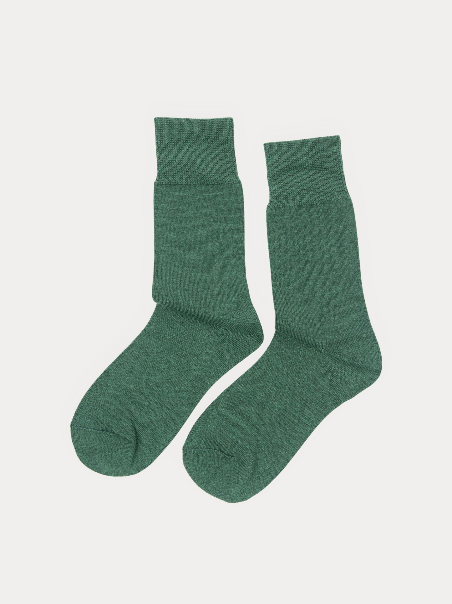 A pair of crew socks laid flat on a light gray background, solid heather forest green.
