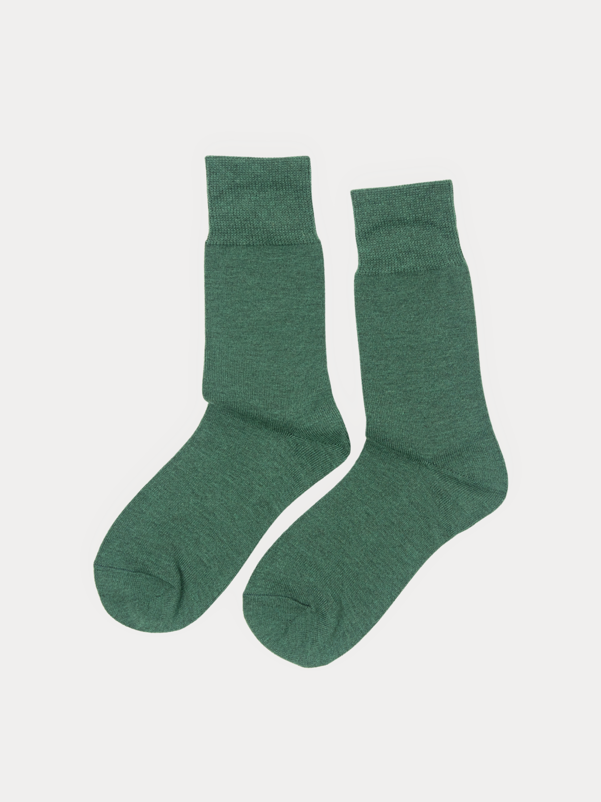 A pair of crew socks laid flat on a light gray background, solid heather forest green.