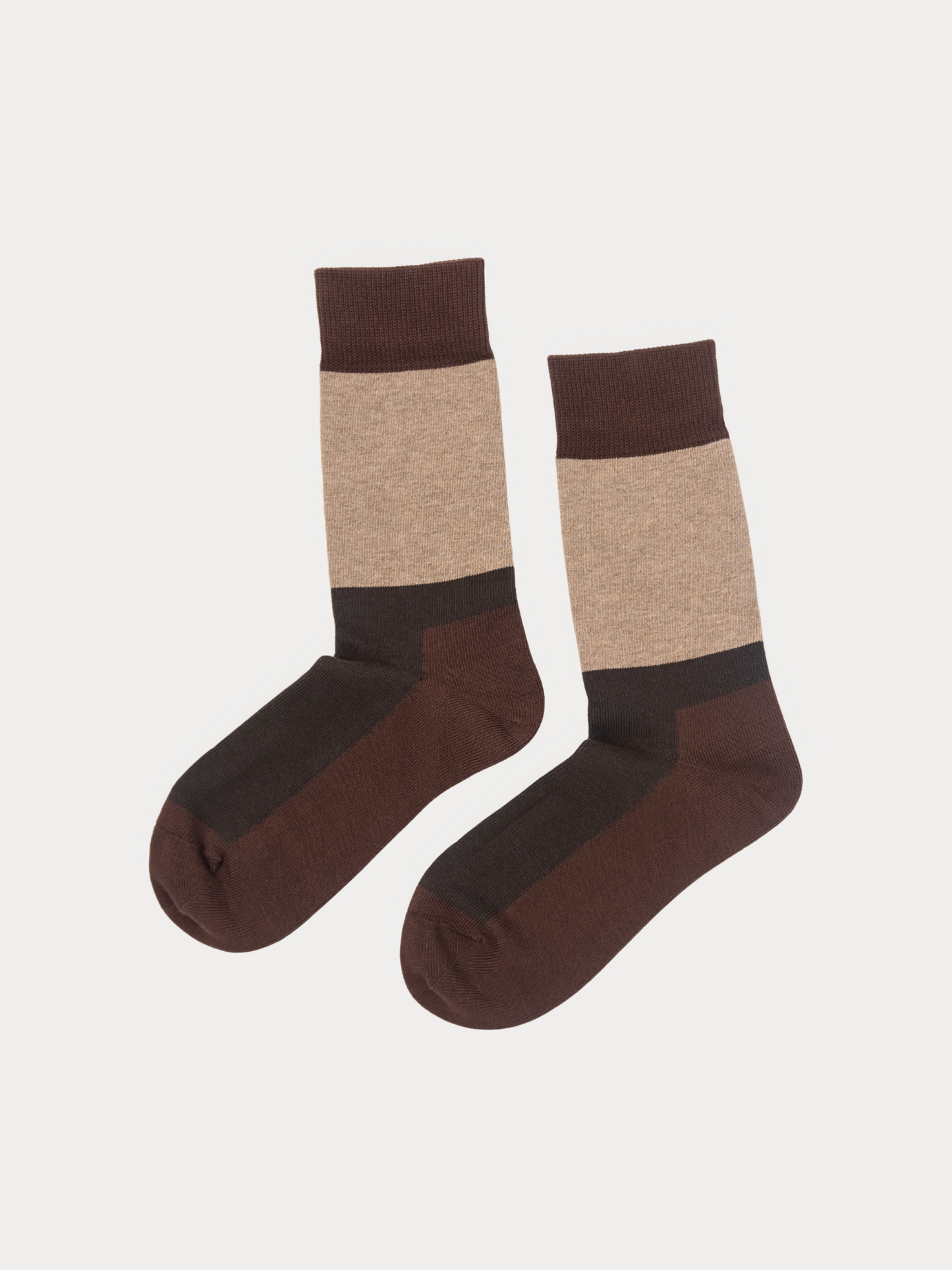 A pair of crew socks with a color-blocked design in dark brown, beige, and black, displayed against a light off-white background.