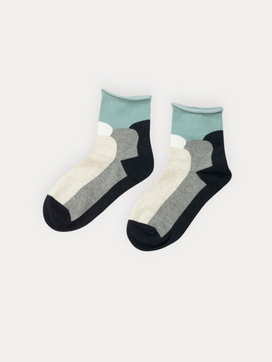 A pair of quarter socks with a rolled mint green cuff and bold color block panels in black, grey, and cream.