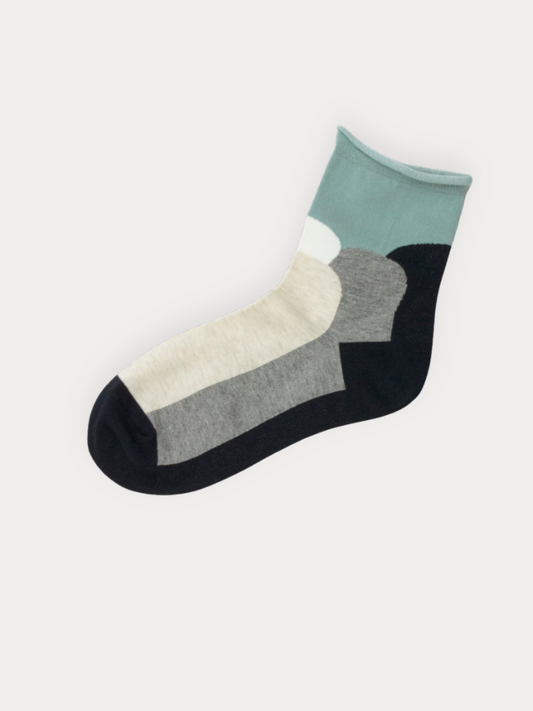 A pair of quarter socks with a rolled mint green cuff and bold color block panels in black, grey, and cream.