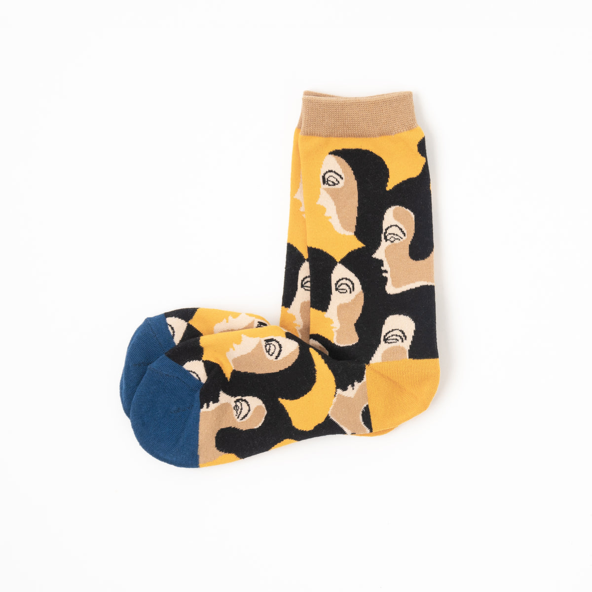 A pair of crew socks featuring a bold graphic pattern of stylized faces in black, beige, and yellow, with a solid navy blue toe and a beige ribbed cuff, displayed on a clean white background.