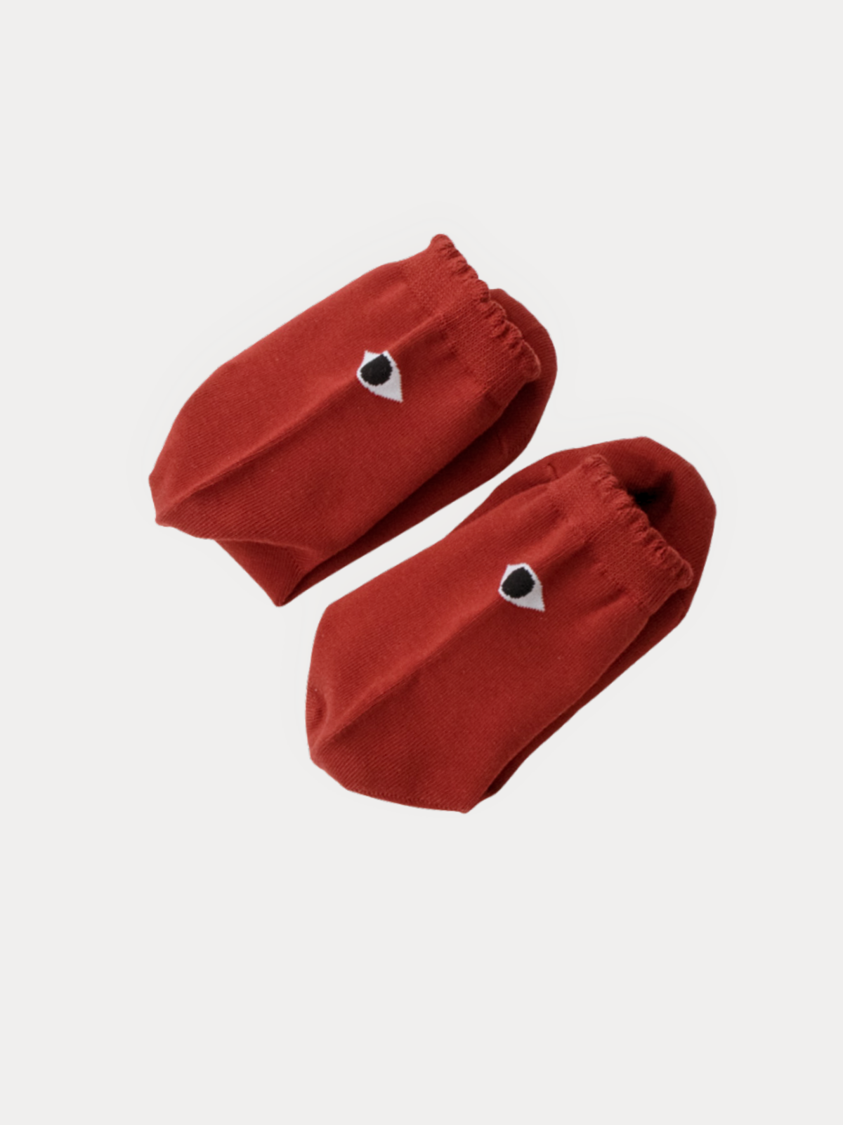 Pair of brick red ankle socks with a small black and white eye graphic on the cuff, folded and overlapping.