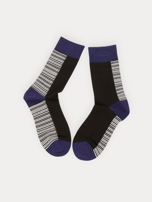 A pair of crew socks in black, white, and navy. Features fine horizontal stripes on the sides and foot, with solid navy cuffs, heel, and toe.