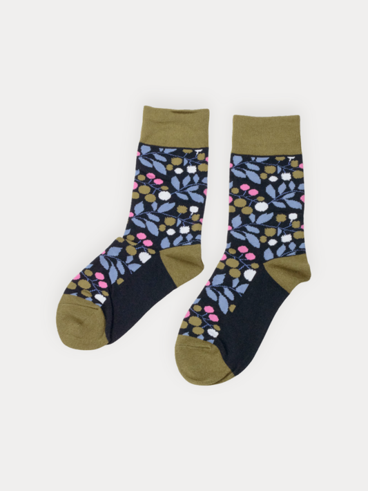 A pair of navy crew socks with a floral and berry print in blue, pink, white, and olive, with an olive green cuff, heel, and toe.