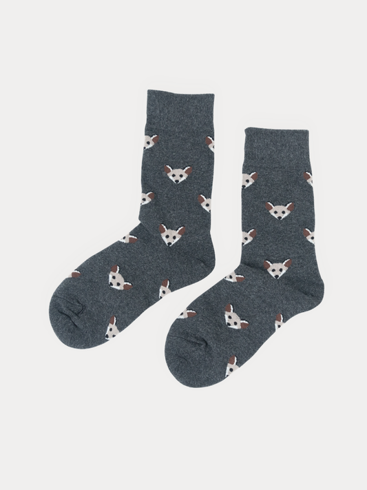 A pair of dark gray crew socks with an all-over repeating pattern of small white and brown fox faces, displayed against a light gray background.