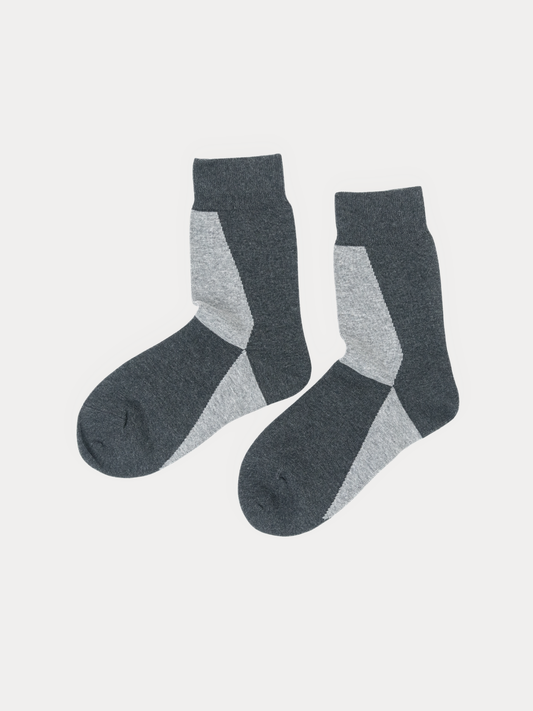 A pair of crew socks in dark gray and light gray with a geometric color-blocked pattern, displayed on a light gray background.