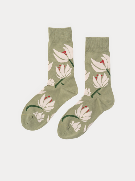 A pair of sage green crew socks with a white lotus floral pattern and small red stamens, displayed against a light gray background.
