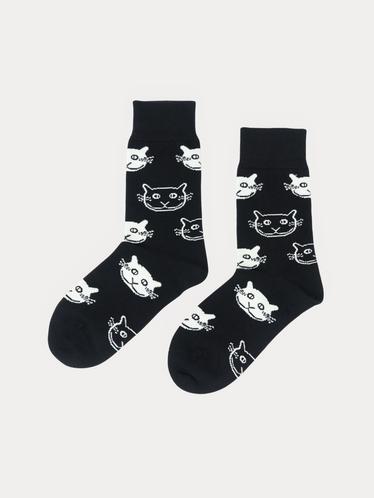 A pair of black crew socks with a white cartoon cat face pattern, displayed against a light gray background.