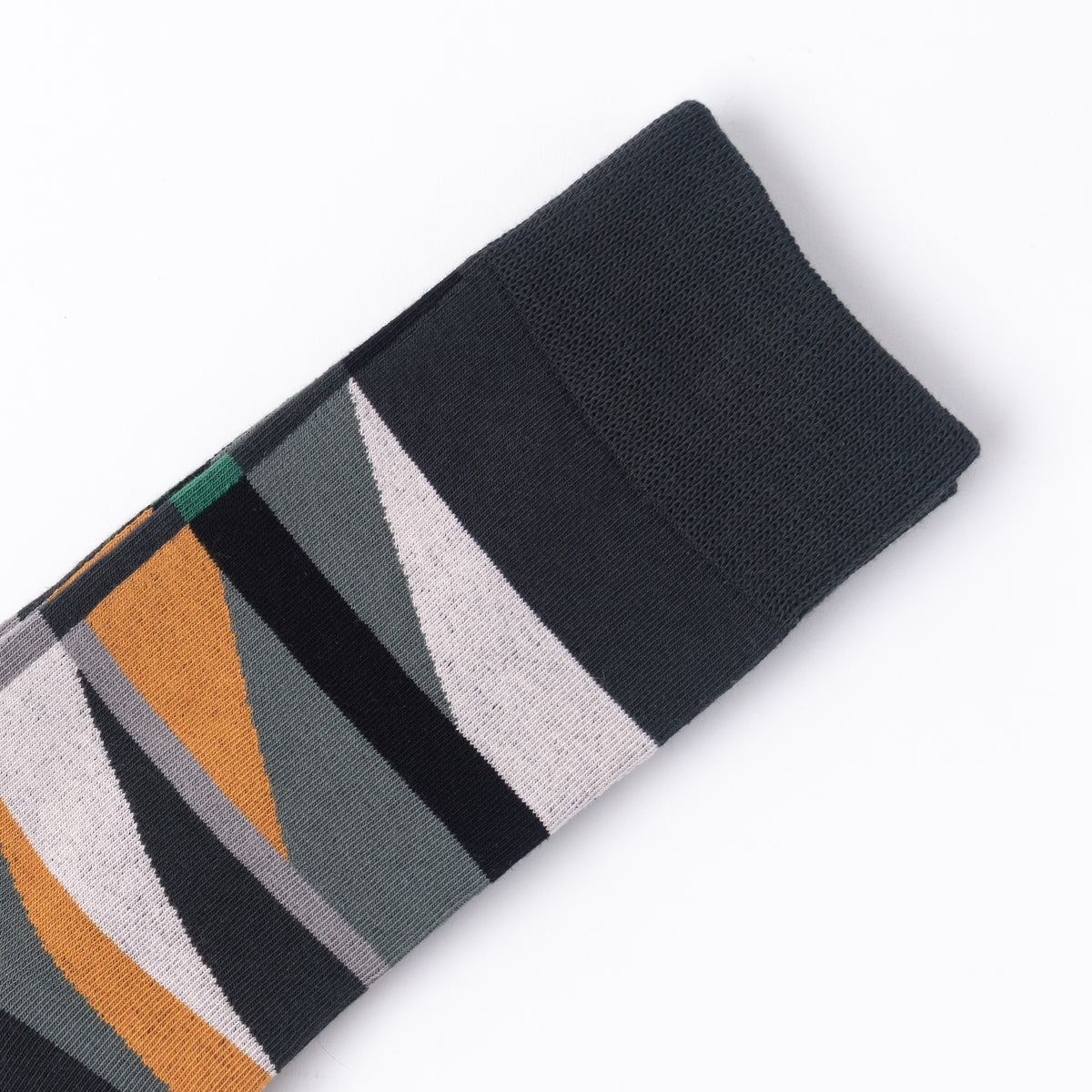 A folded knit sock with a geometric pattern of black, gray, white, and mustard yellow triangles, shown on a clean white background.