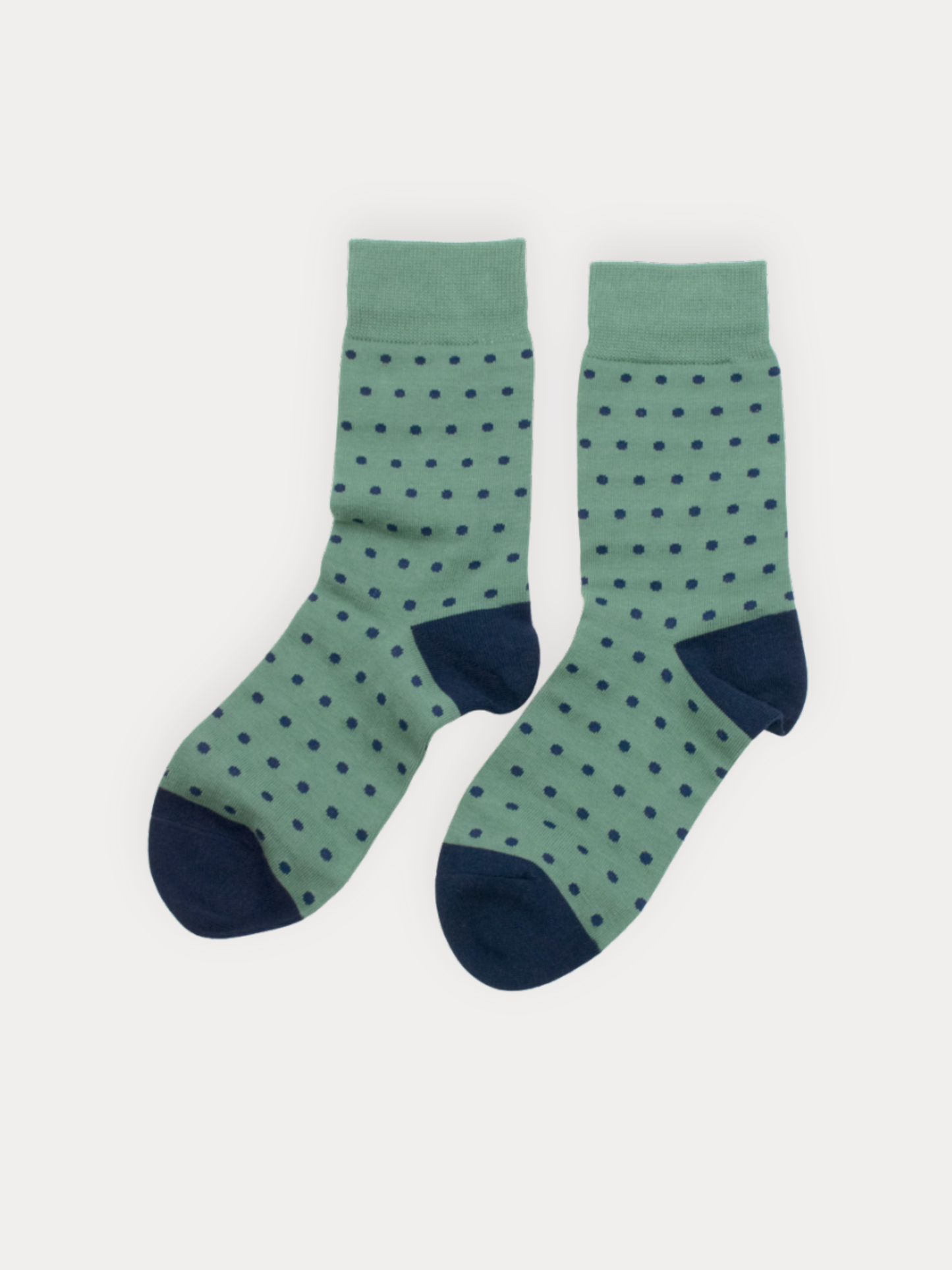 Pair of green socks with navy polka dots on a white background