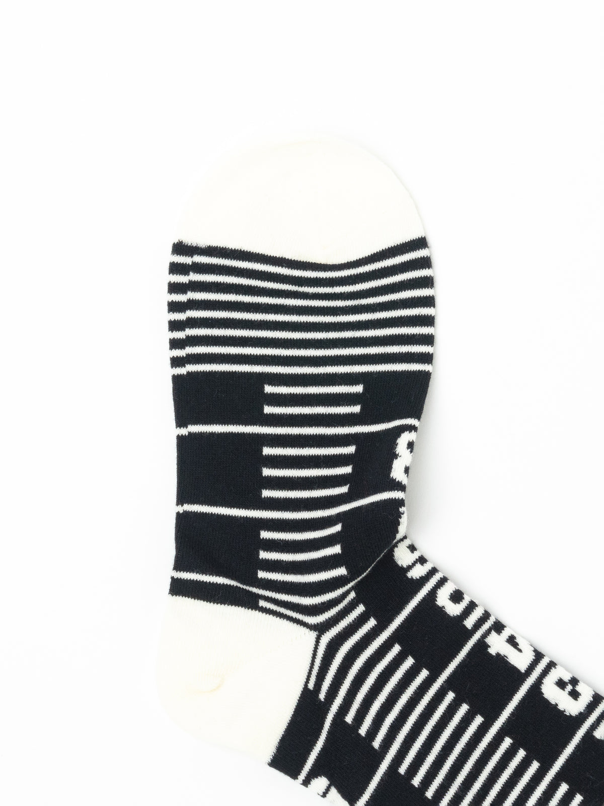 Close-up of one sock foot with cream toe and heel, black body, and horizontal cream stripes across the arch.