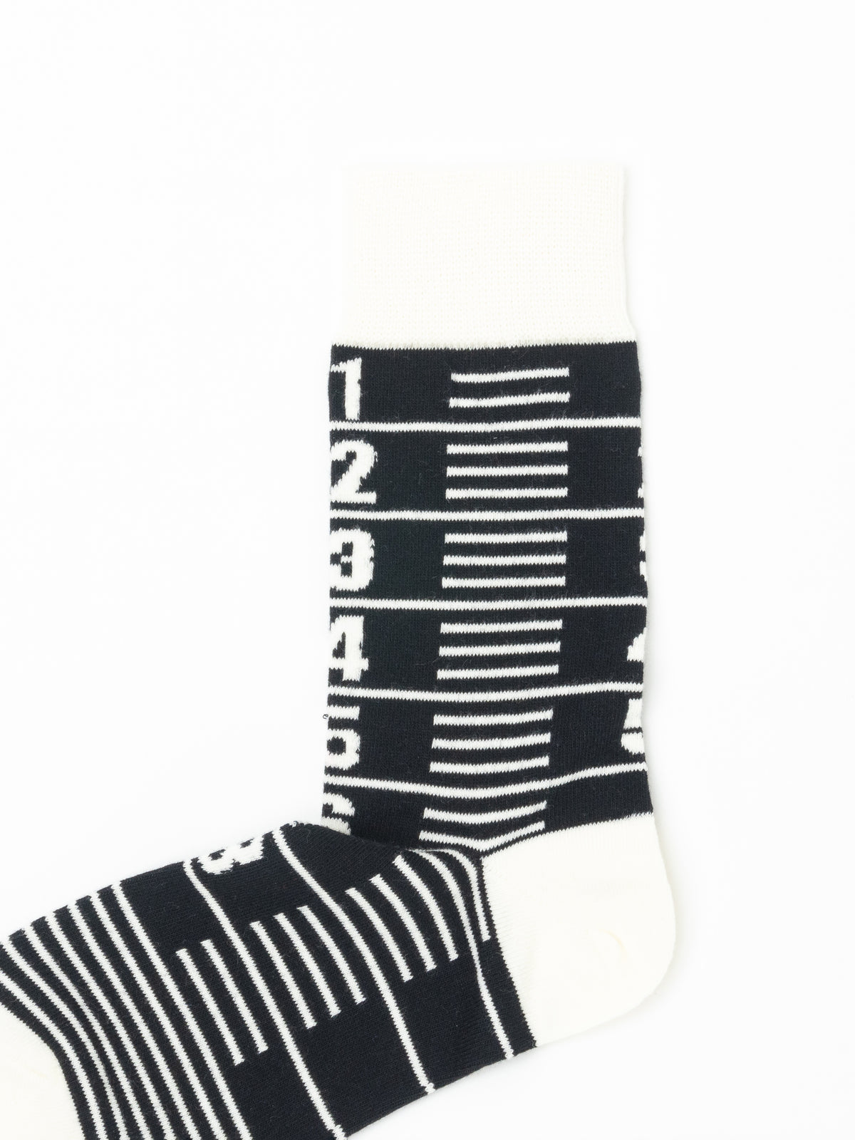 Close-up of the sock leg: numerals 1 through 5 and measuring-tape tick marks knitted in cream on black.