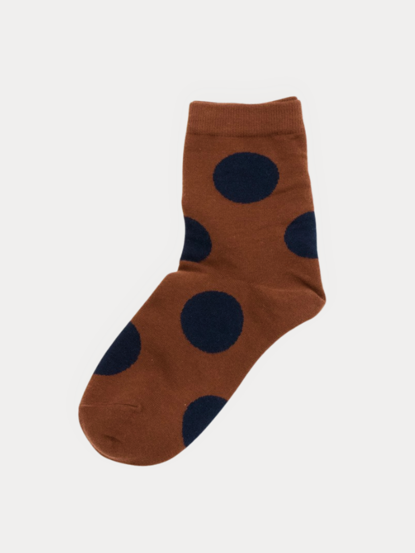 Pair of rust brown quarter socks with large navy polka dots, laid flat.