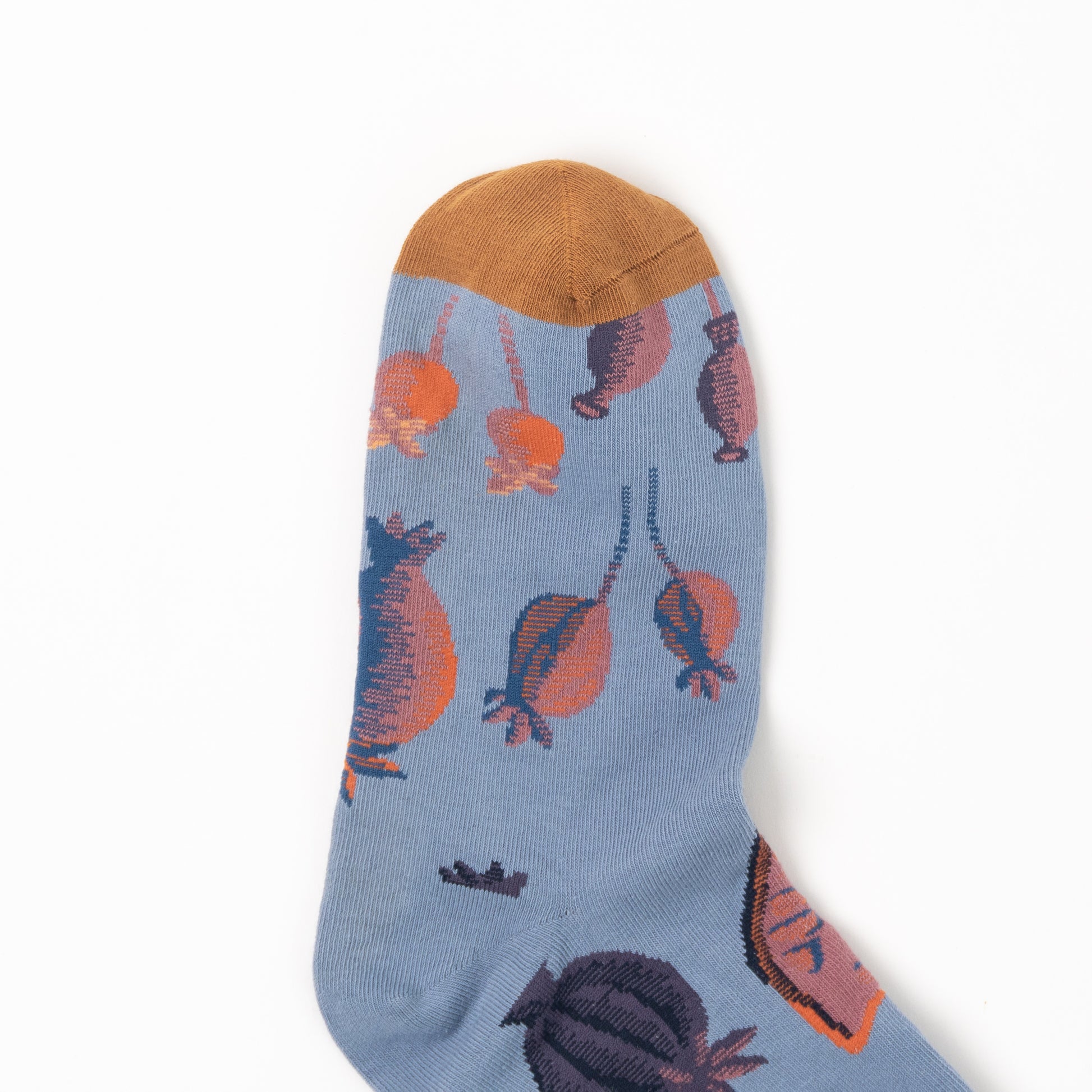 Close-up of a sock's mustard gold toe, with orange and plum poppy pods scattered across the dusty blue foot.