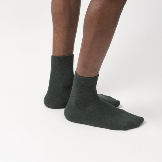 A close-up side angle of short forest green quarter socks worn on a model against a white background.