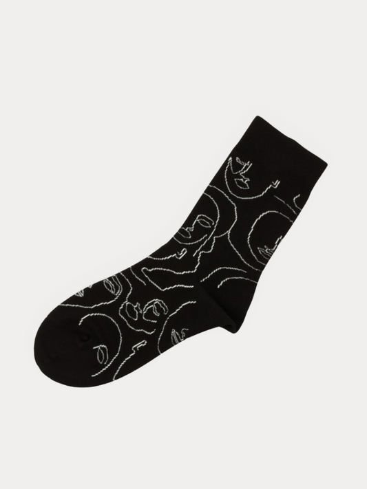 A single black crew sock with a white continuous line art pattern of stylized faces, shown against a light gray background.