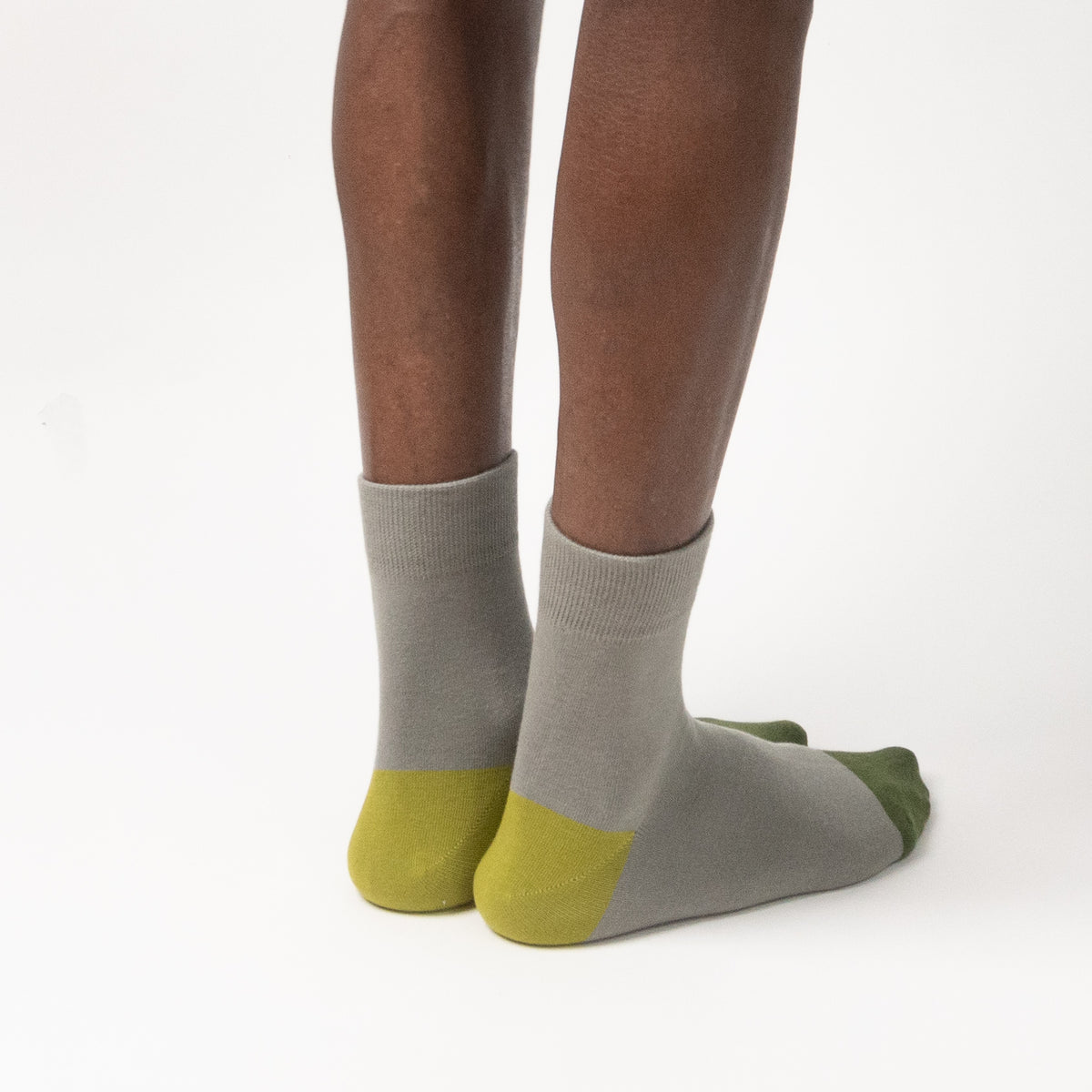 Gray ankle socks with olive green toes and heels, shown on a person's feet against a plain white background.
