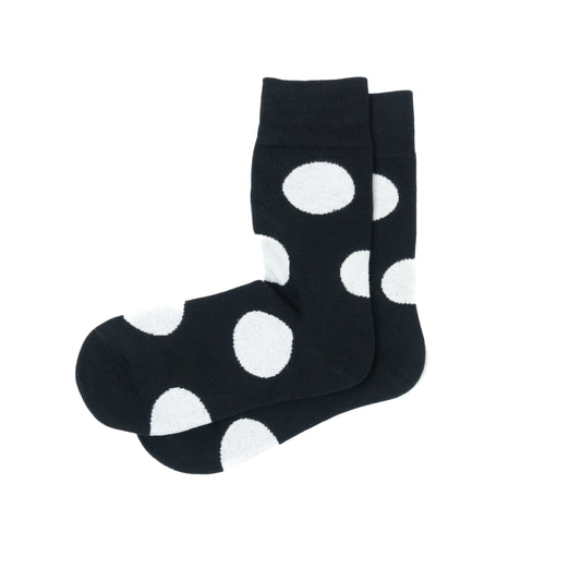 Pair of black crew socks with a bold white polka dot print, laid flat and overlapping at the ankle.