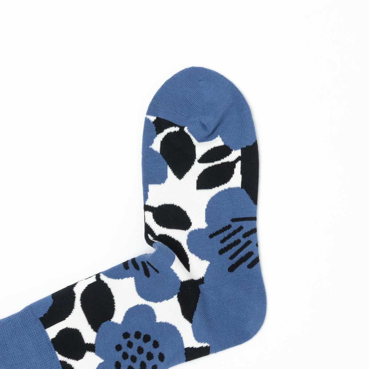 Close-up of the toe of a blue crew sock with a bold black and white floral print.