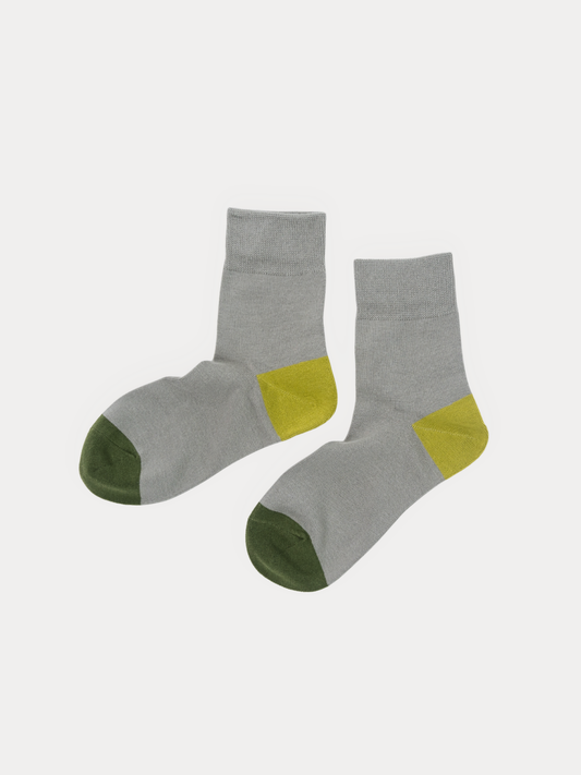 A pair of crew socks in heather gray with olive green toes and yellow heel accents, displayed against a light gray background.