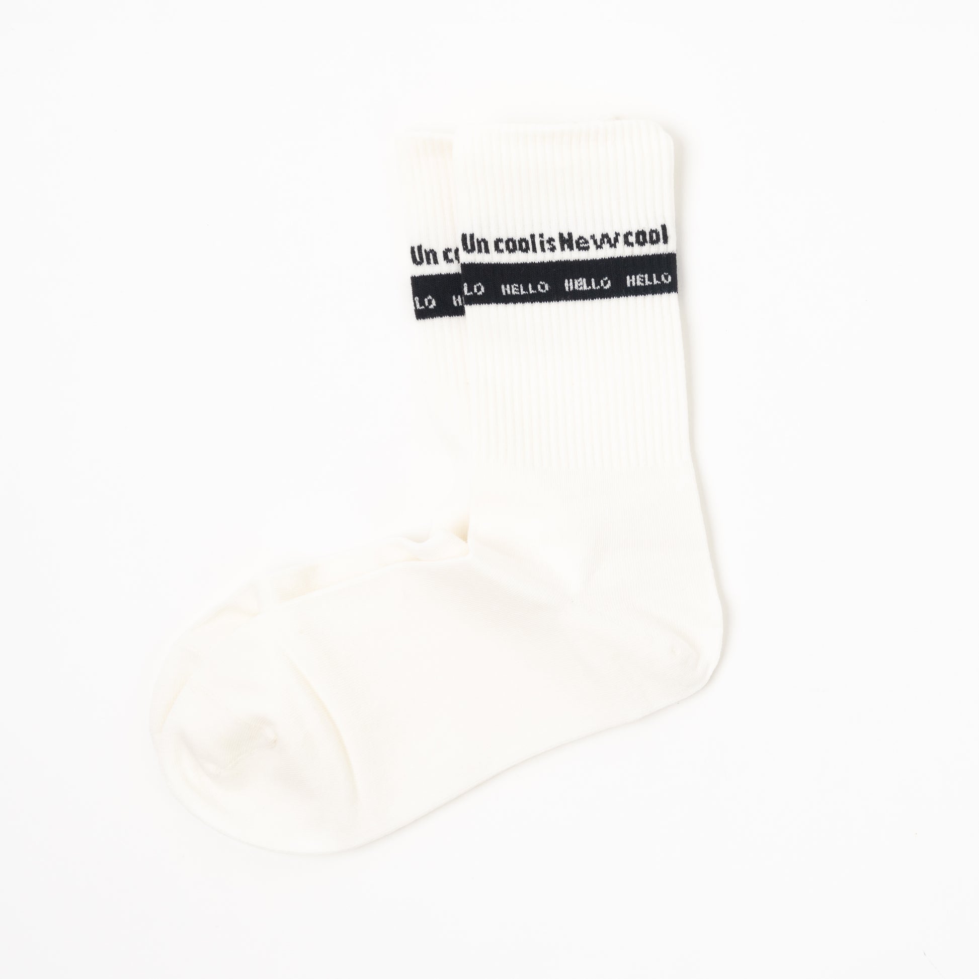A single off-white crew sock with a black band near the cuff featuring the text 'uncool is new cool ' and 'HELLO' repeated, shown on a plain white background.